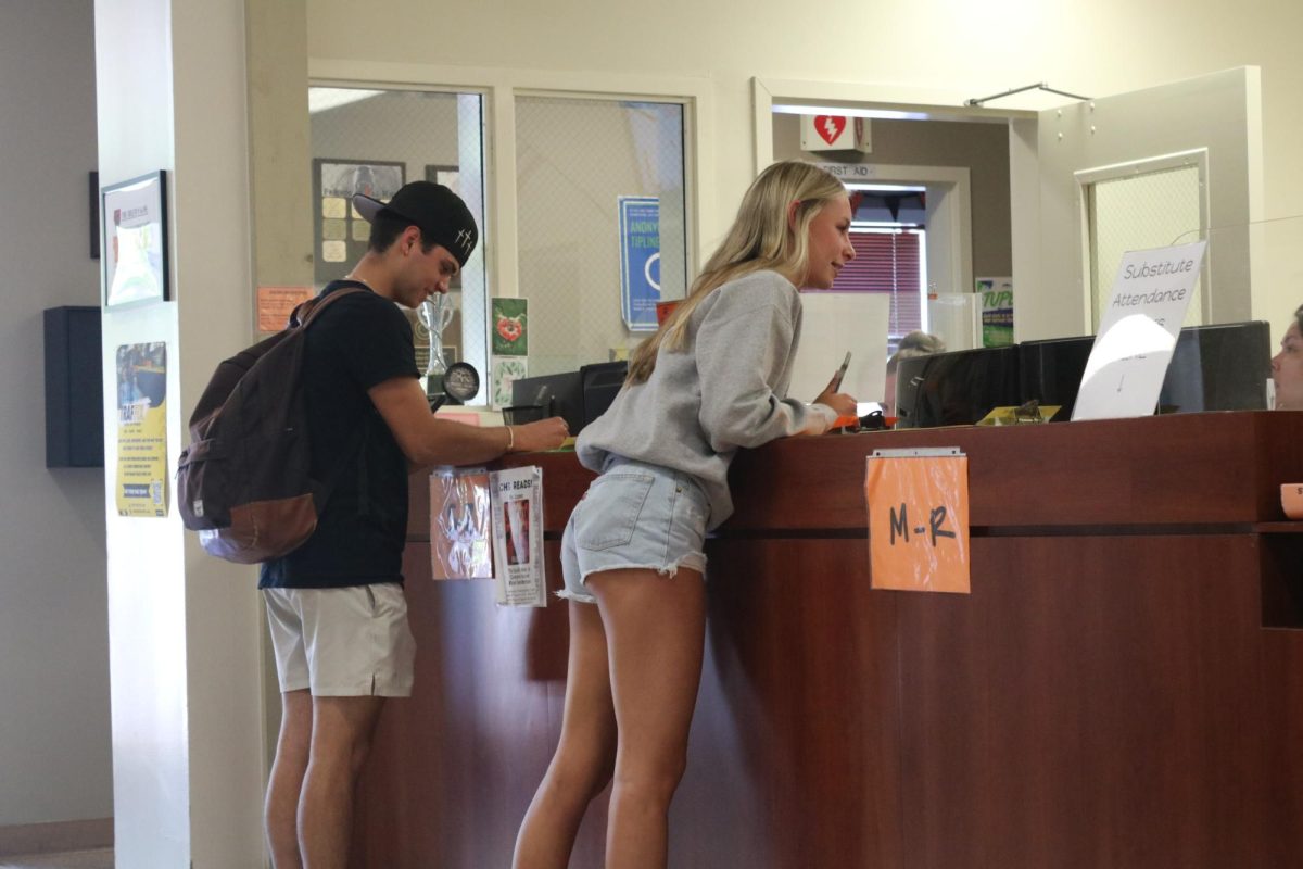 Sophomore Ava Petteruti, right, signs out of school with the attendance secretaries in the front office.