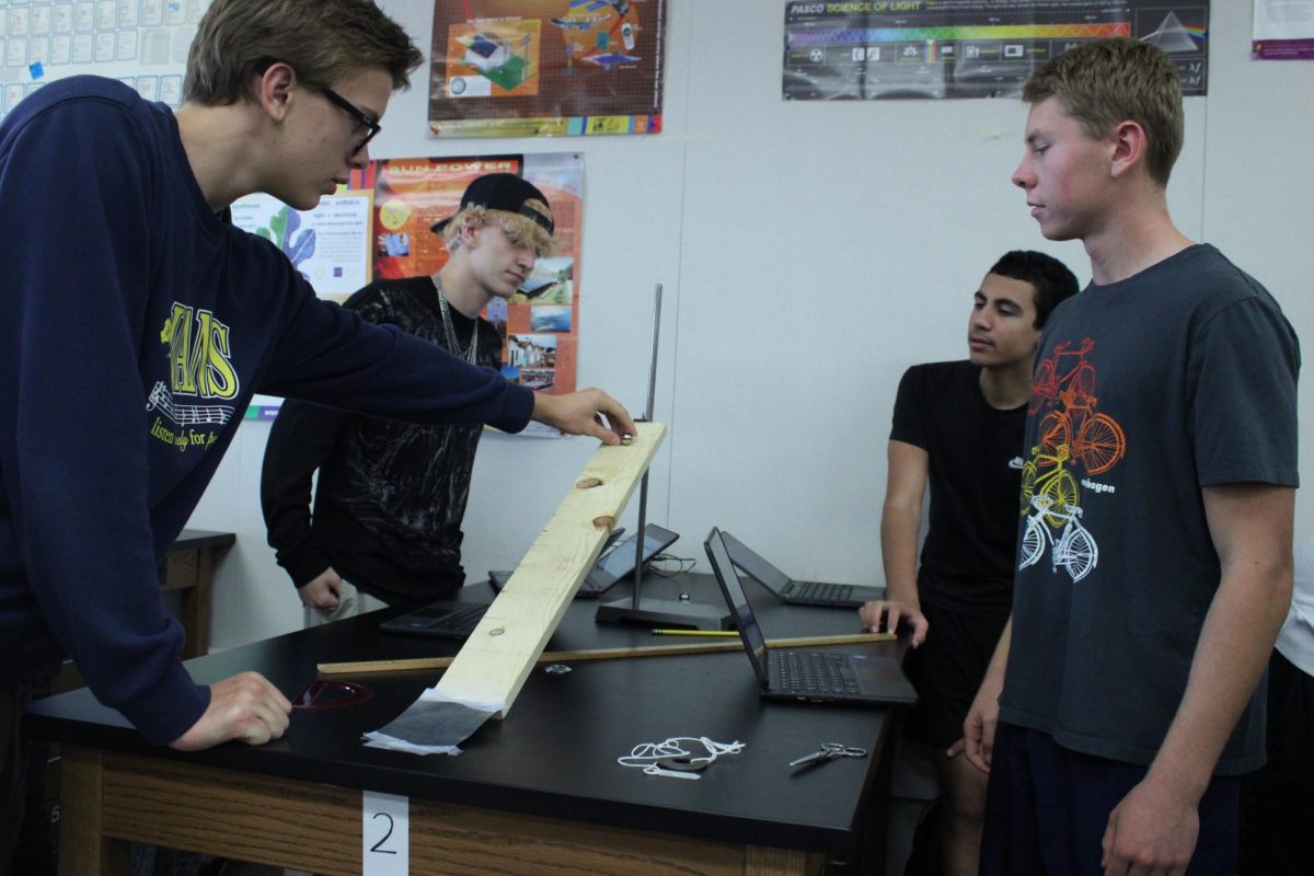 Students in teacher Keith Callerame’s physics class measure the displacement of a metal ball for a lab in honors physics teacher Fred Wafula’s classroom, which features lab tables 