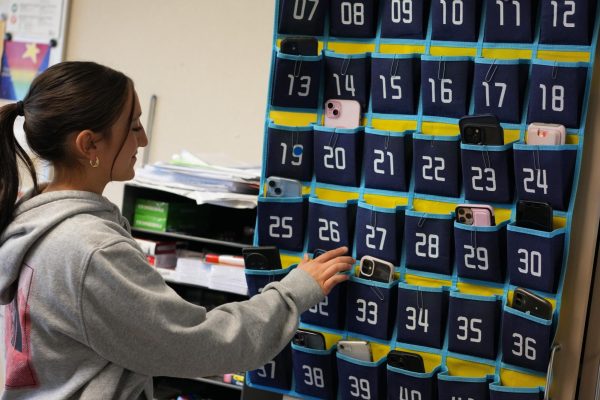 Freshman Nabila Haqiq puts her phone in a wall caddy. Many teachers at Cal High use phone jails and wall caddies to prevent student phone use during class and lesson time.