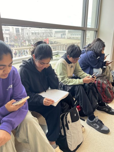 Staff writer Gayatri Nair (second from left) does her homework without her phone, while, from left to right, sophomores Sahana Nagandla, Siva Saravanan, and Anaika Khatod scroll on their phones during lunch. 